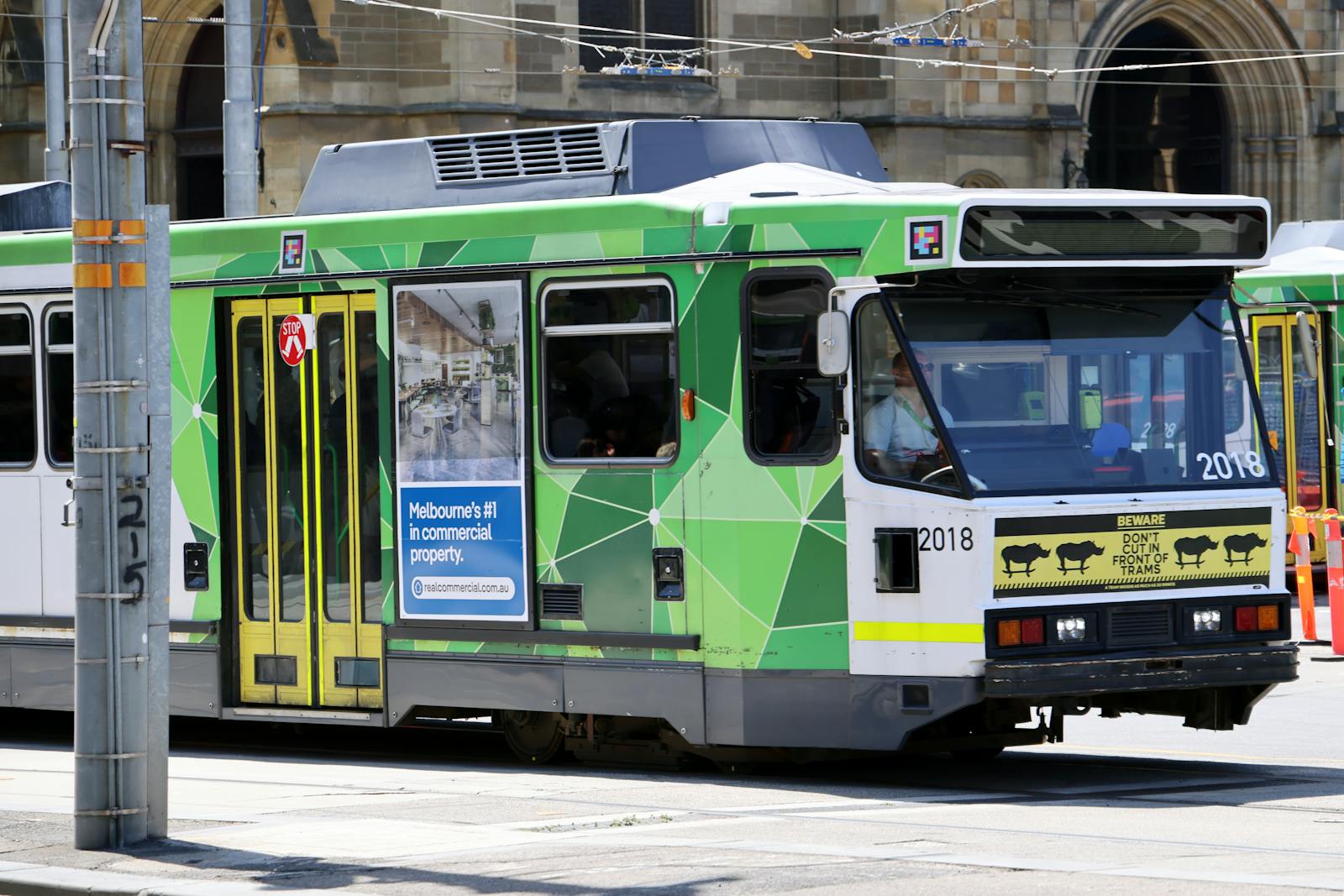 A classic green Melbourne tram traversing a city street