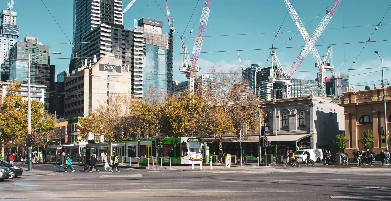 A safe, busy Melbourne city street with pedestrians and trams during the day