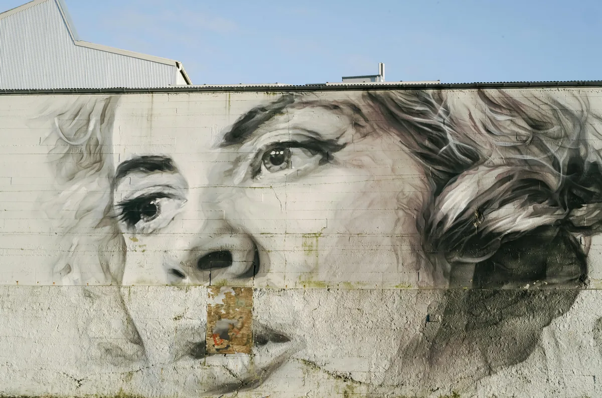 A large-scale portrait mural by a Melbourne street artist on a building wall