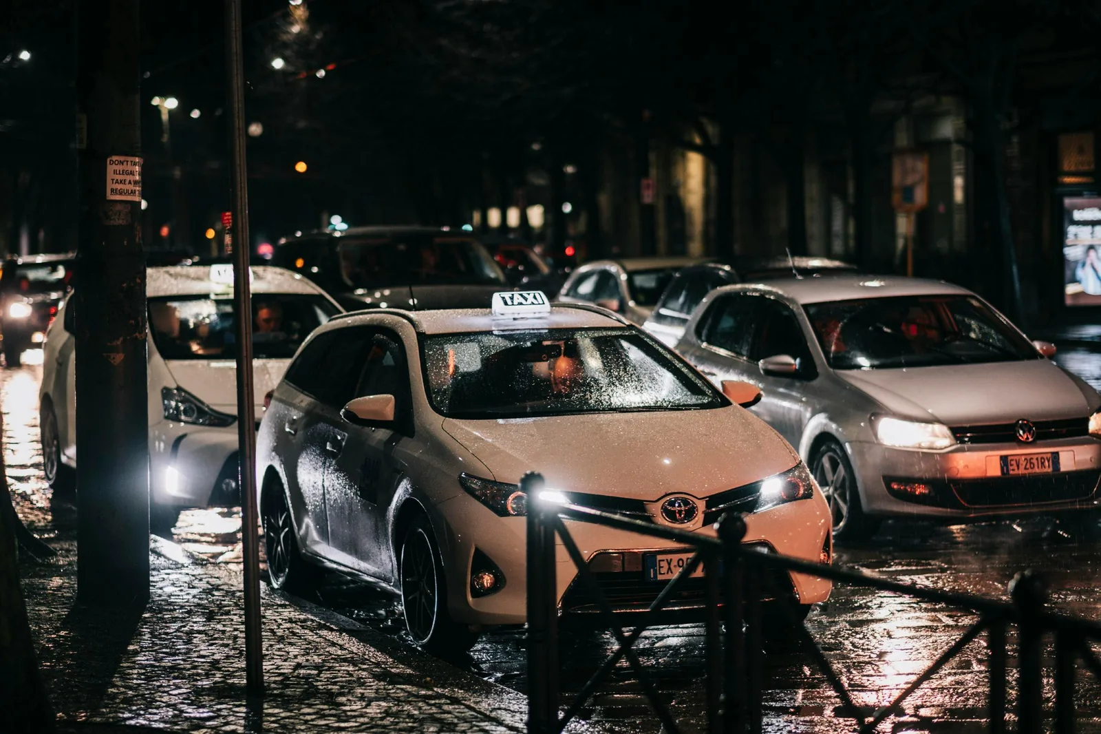 A rideshare car and taxi on a Melbourne city street at night