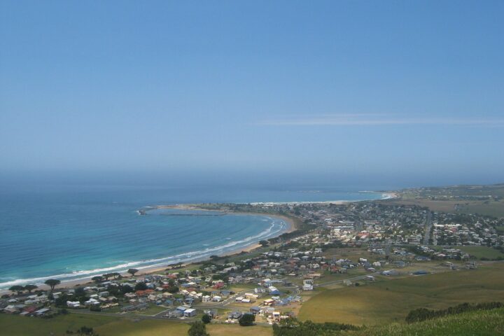 Apollo Bay seen from Mariners Lookout, with the curved beach, harbour breakwater and town spread below green hills