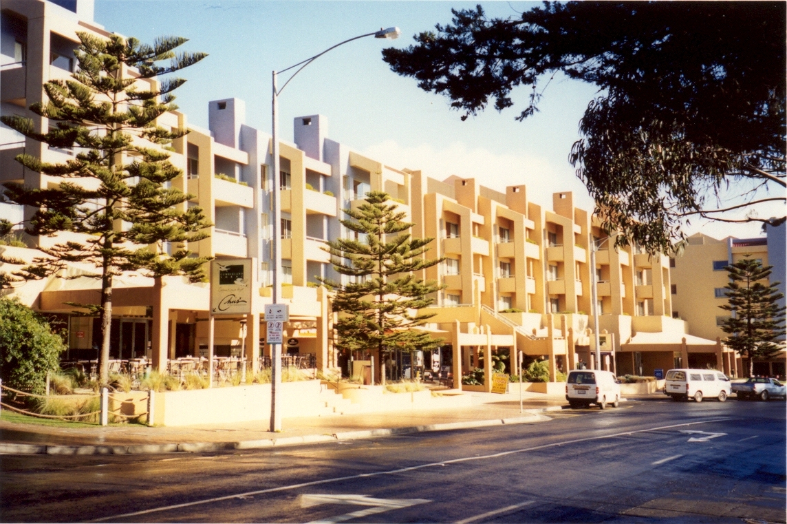 The low-rise Cumberland Lorne Resort building with balconies behind Norfolk Island pines on Mountjoy Parade in Lorne