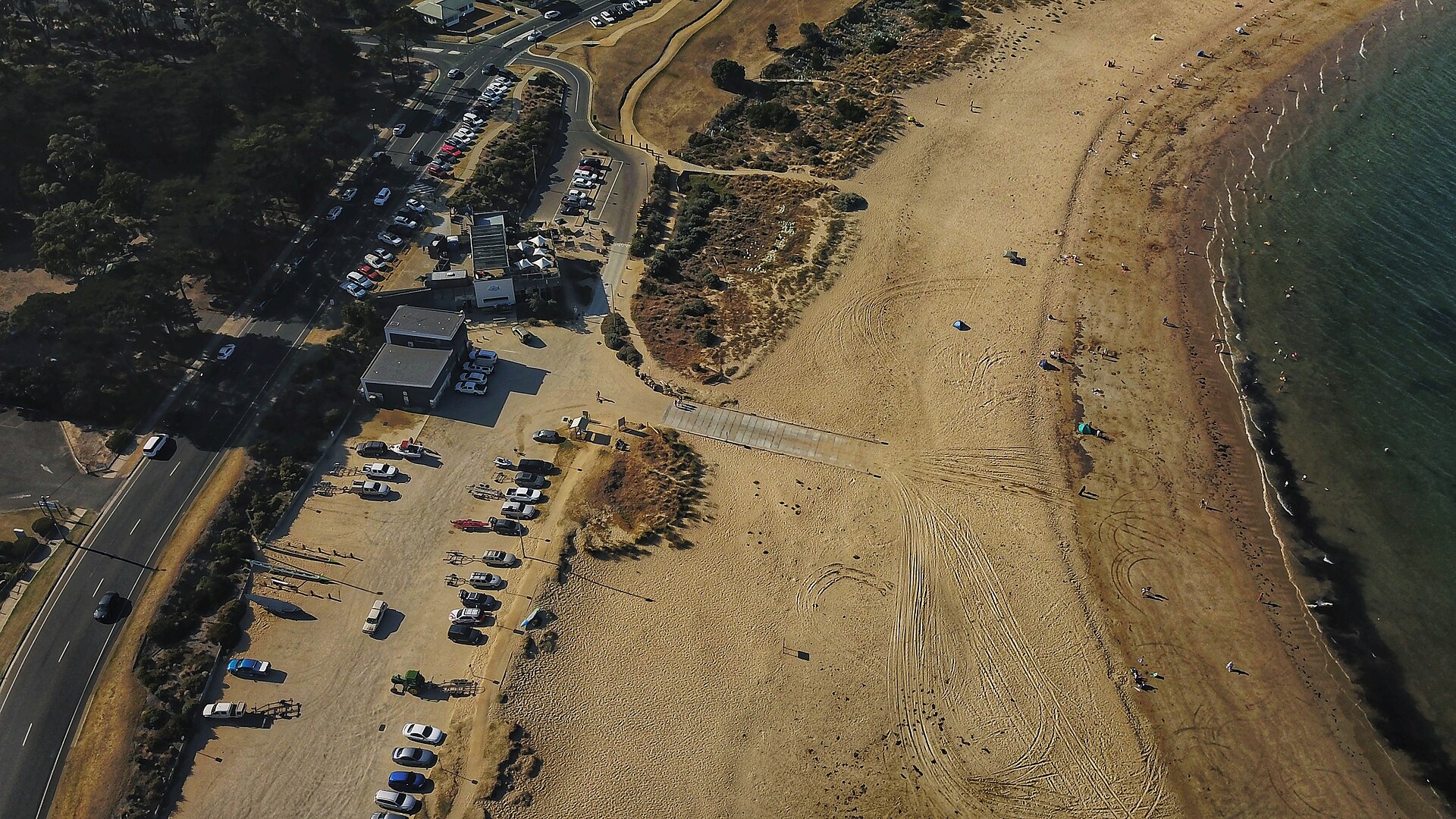 Aerial view of Fishermans Beach at Torquay, with a boat ramp, car park and beachfront restaurant beside a wide sandy beach