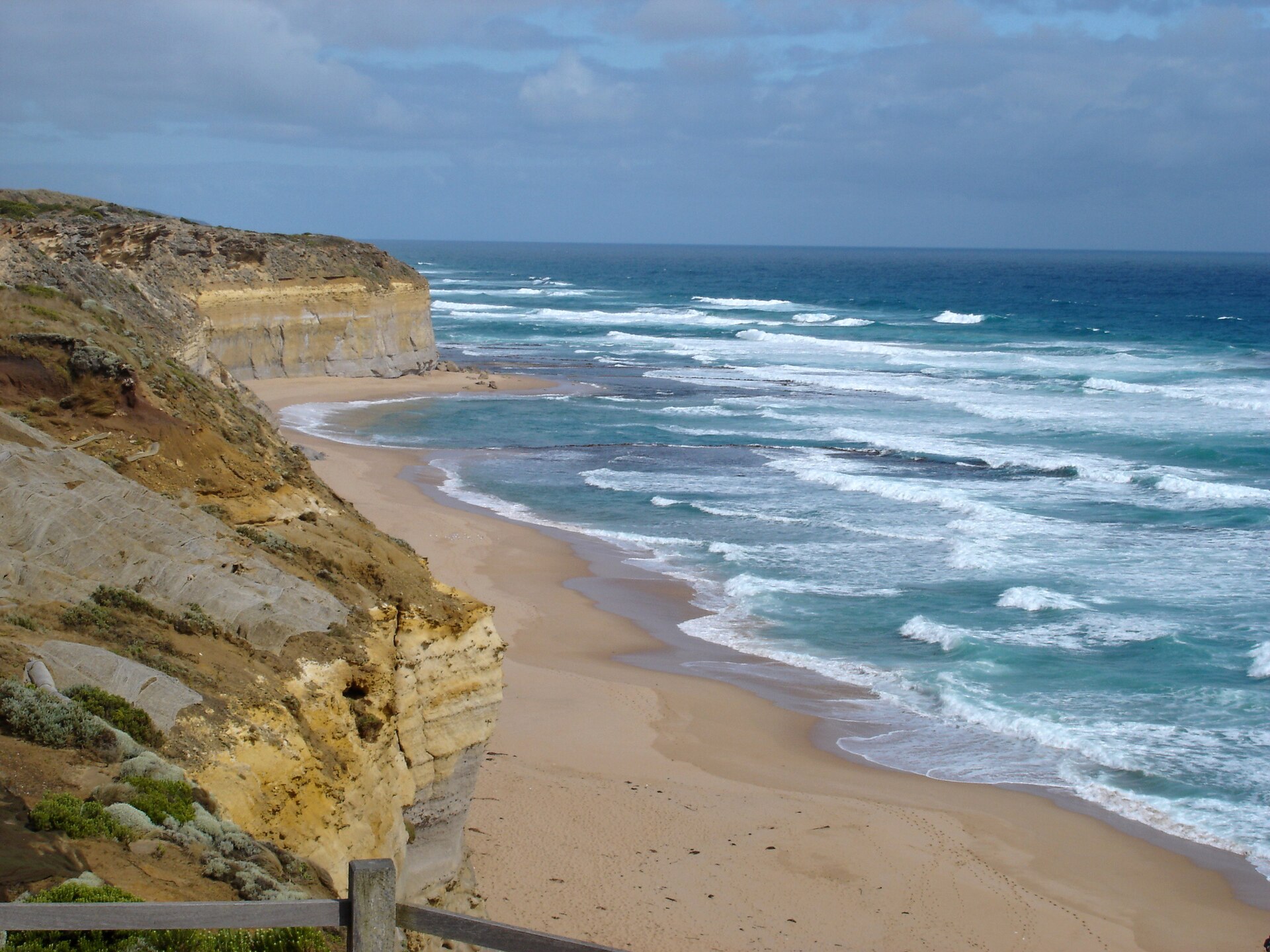 Gibson Beach seen from the top of the steps, a long curve of sand under golden limestone cliffs with white surf